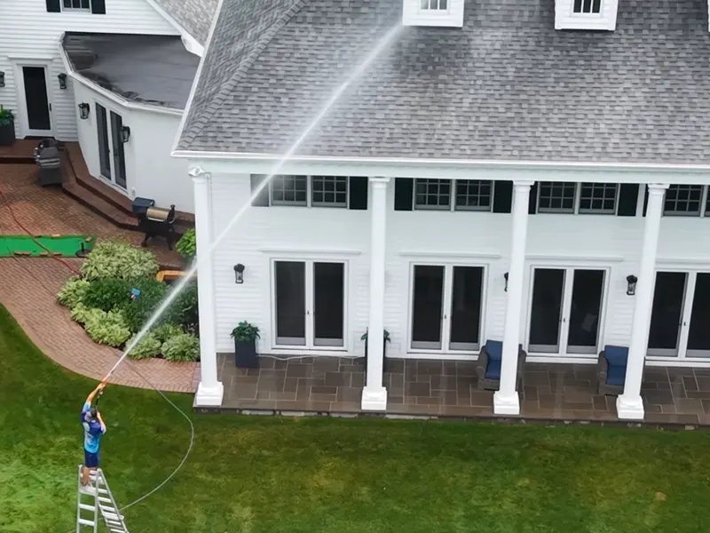 Our crew soft washing a white colonial home, from above
