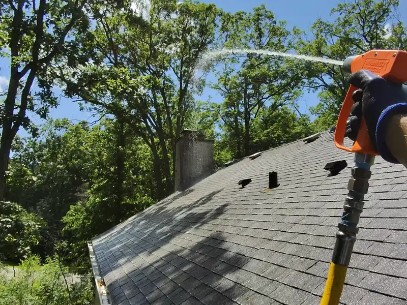 Our crew soft washing an asphalt shingle roof